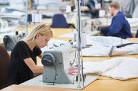 A woman sitting at a sewing machine in a garment factory