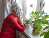 An old woman in a home wearing a mask against covid